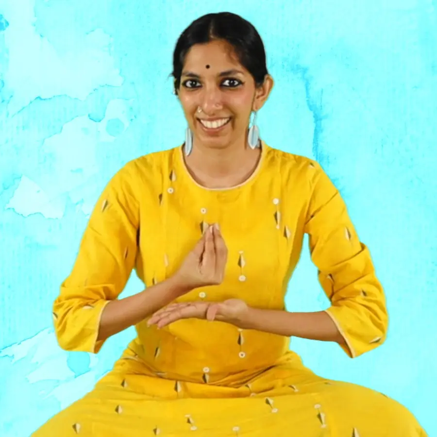 Priya, a teacher, sitting cross-legged with one hand pinched upright over her flat palm